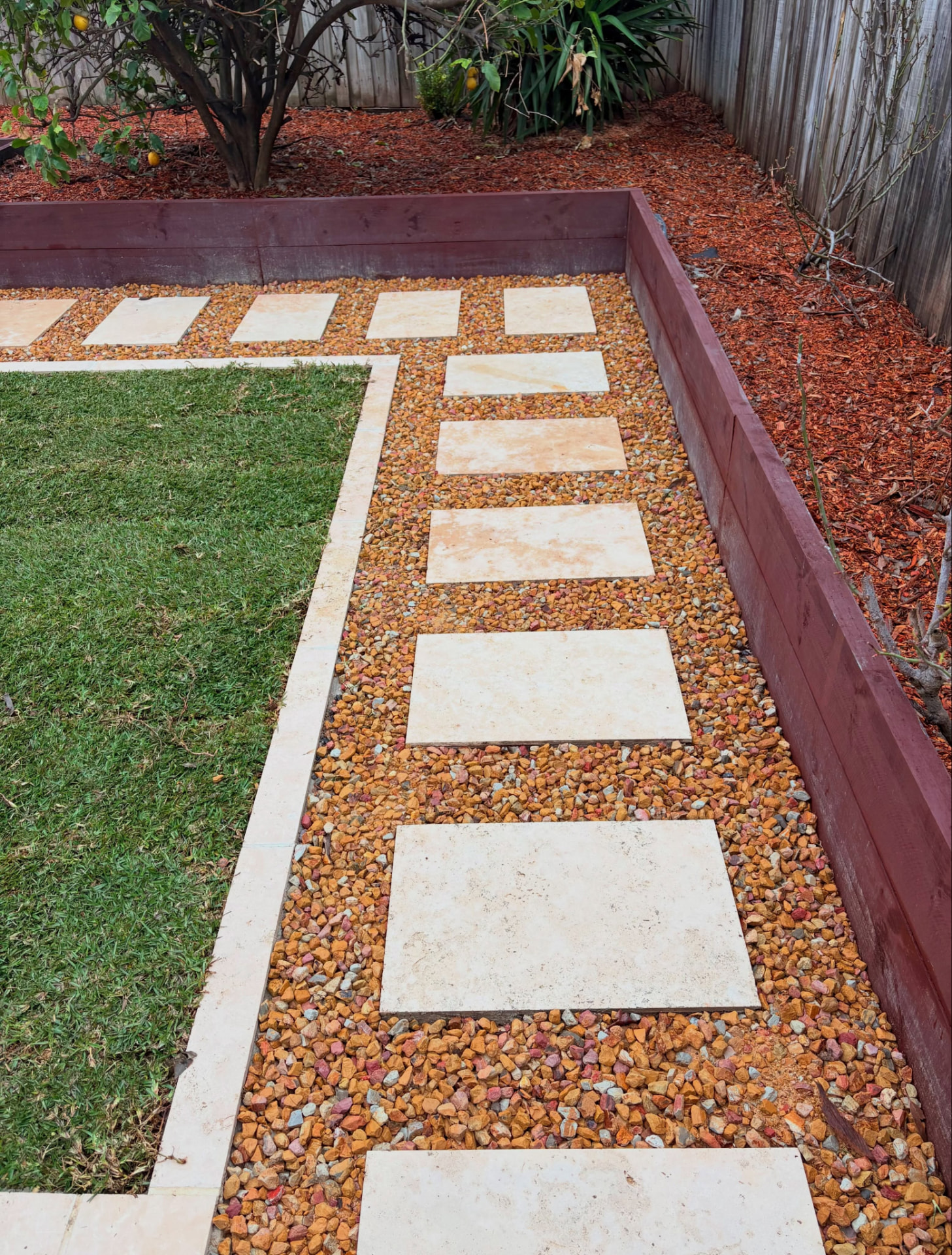 Square pavers set in red gravel beside turf